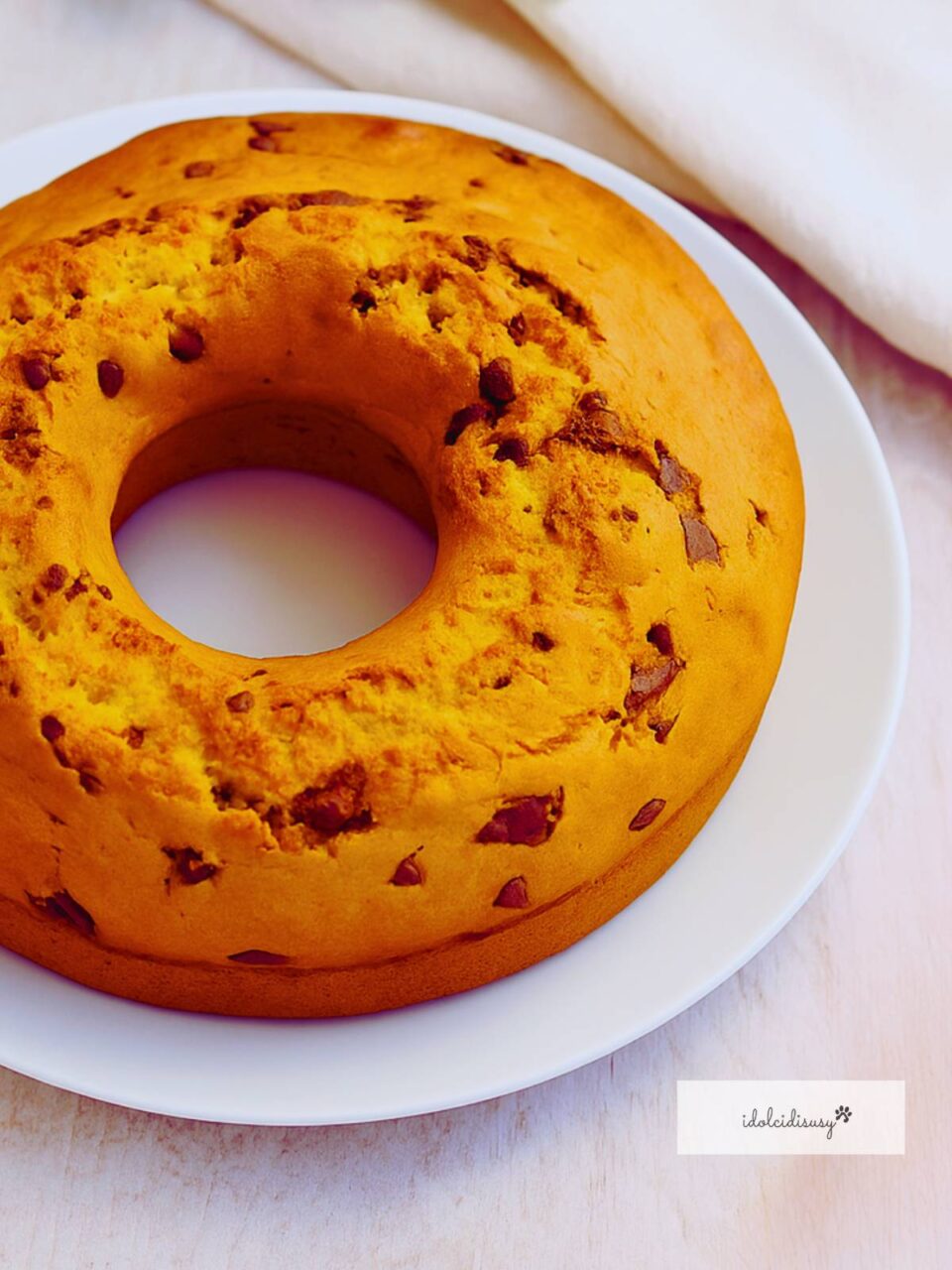 Ciambellone soffice con pezzi di cioccolato, ricetta Bimby, servito su piatto bianco.