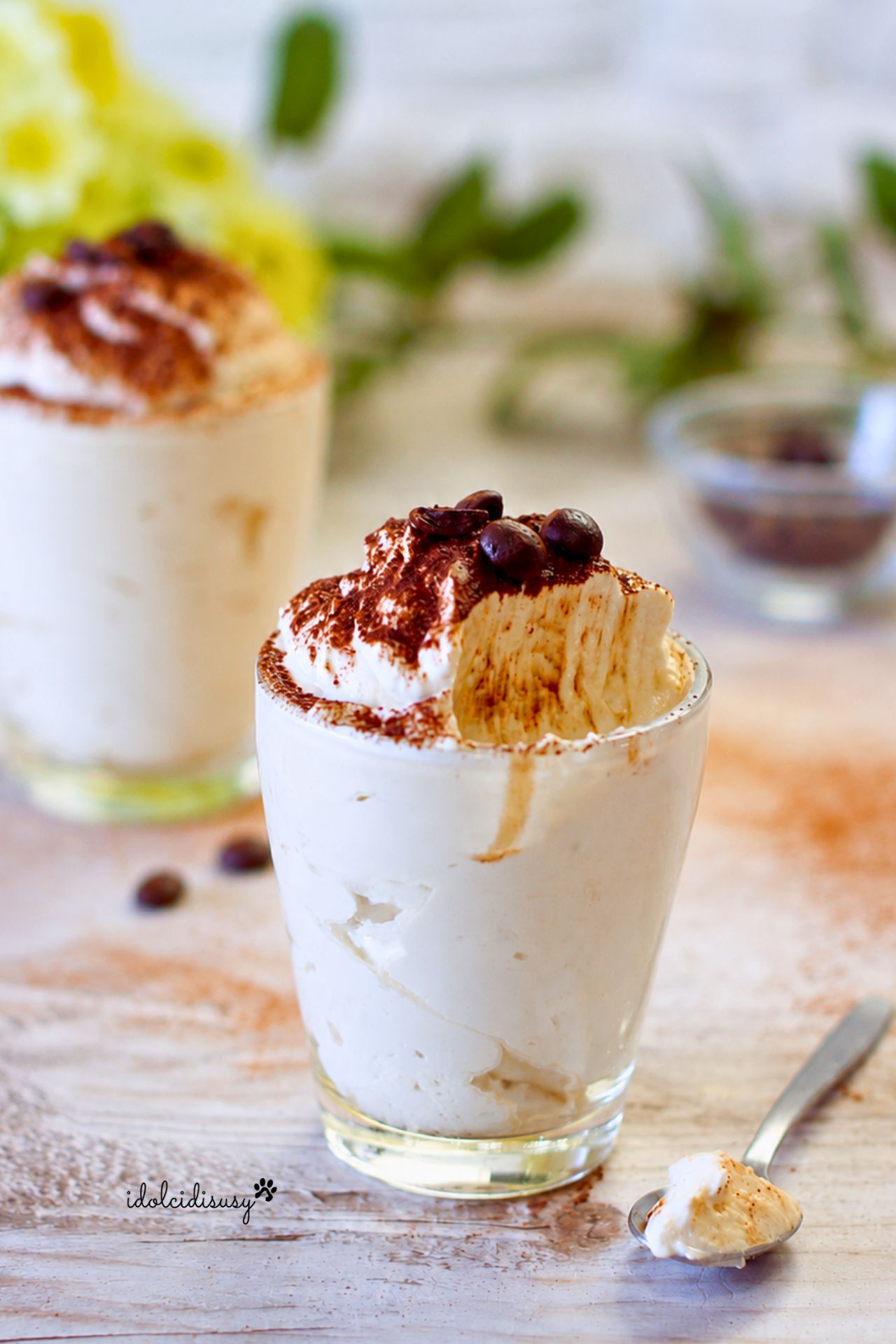 Crema fredda al caffè con mascarpone e panna in bicchiere di vetro con cucchiaino e decorazione al cacao.