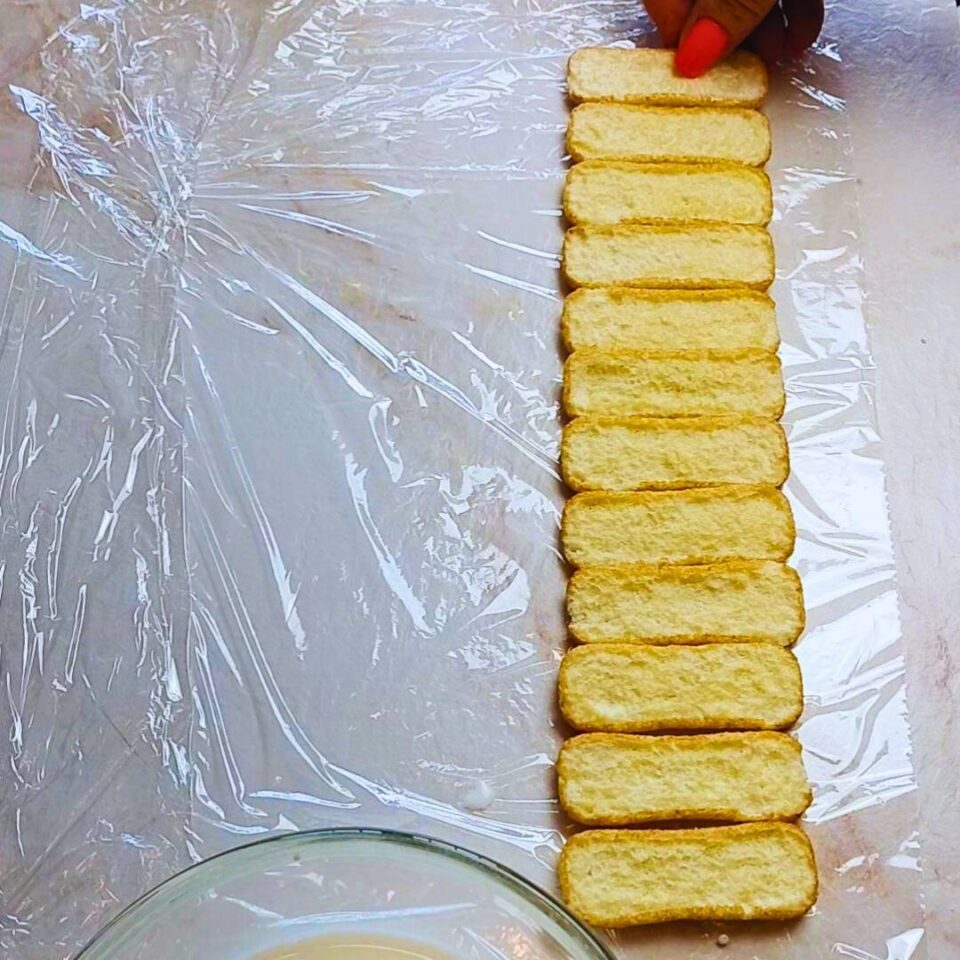 Prima fila di savoiardi bagnati disposti su pellicola trasparente