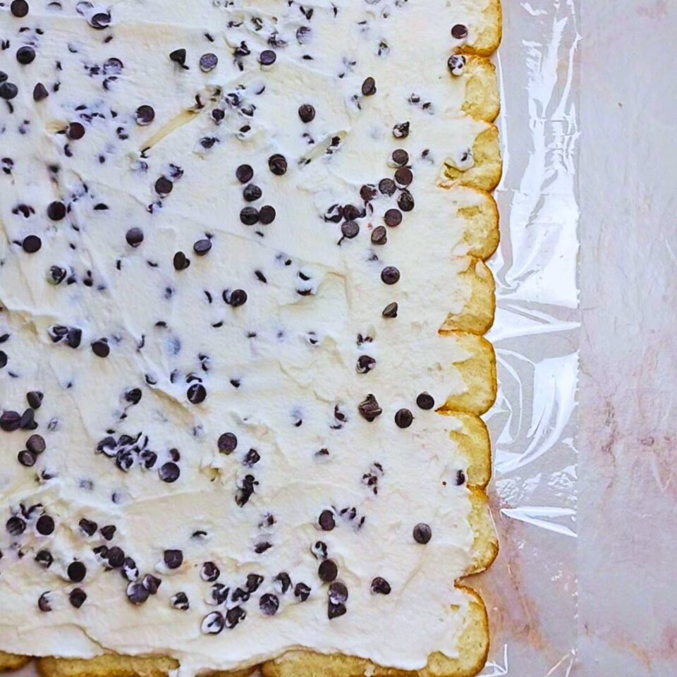 Strato di crema al mascarpone con gocce di cioccolato sopra i savoiardi