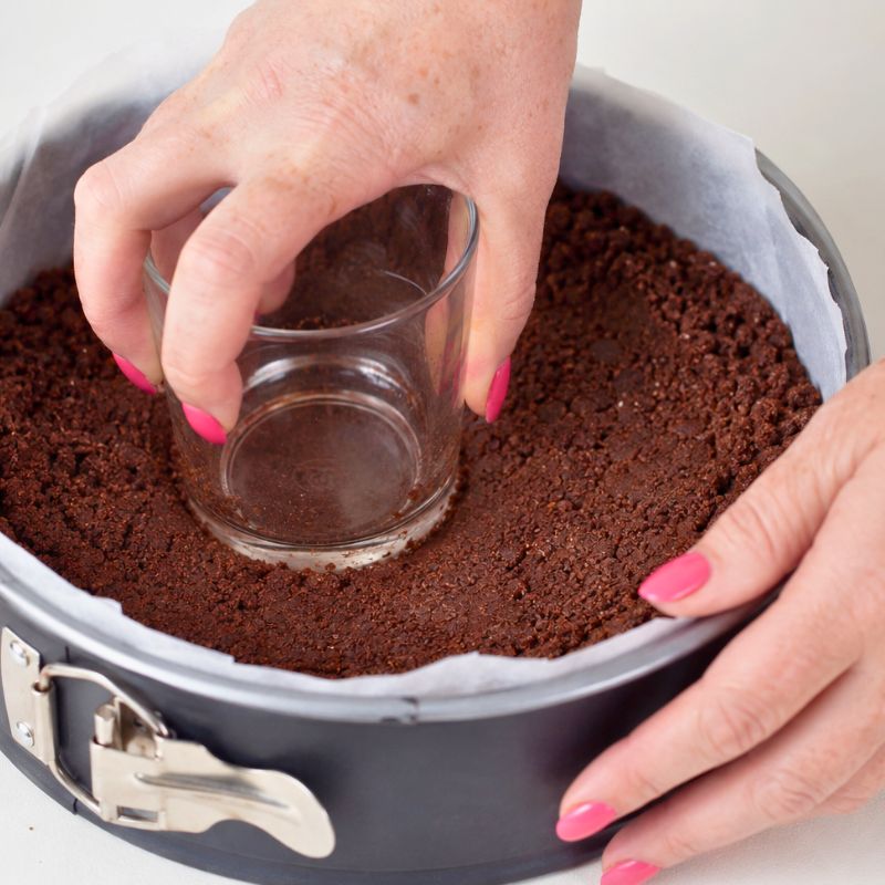 Preparo la base della torta fredda compattando i biscotti al cacao nello stampo.