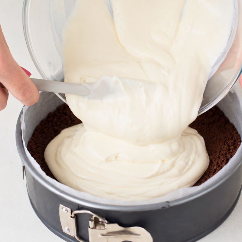Verso la crema bianca allo yogurt sulla base di biscotti al cacao.