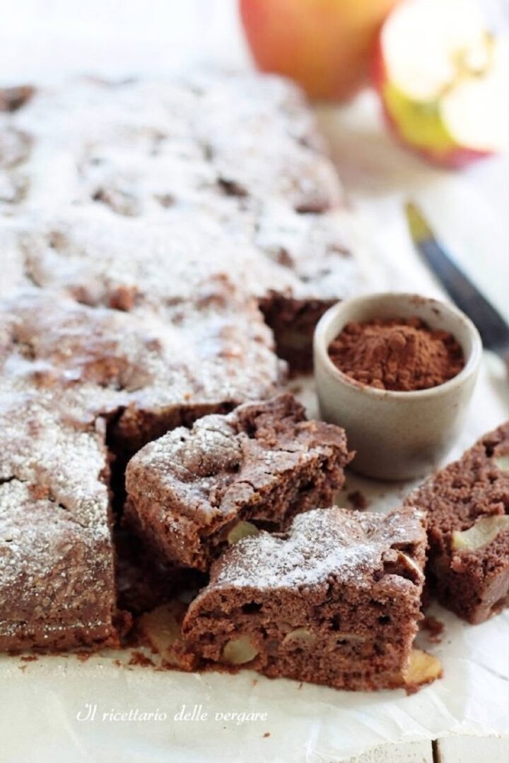 Fetta di dolce al cacao e mele vicino a una ciotolina di cacao in polvere