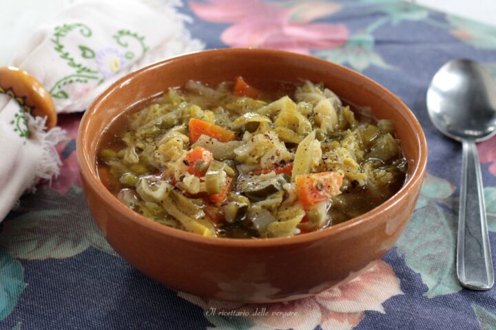 Una ciotola di zuppa di verdure calda con verza, porri, piselli e zucchine, servita in una ciotola di terracotta