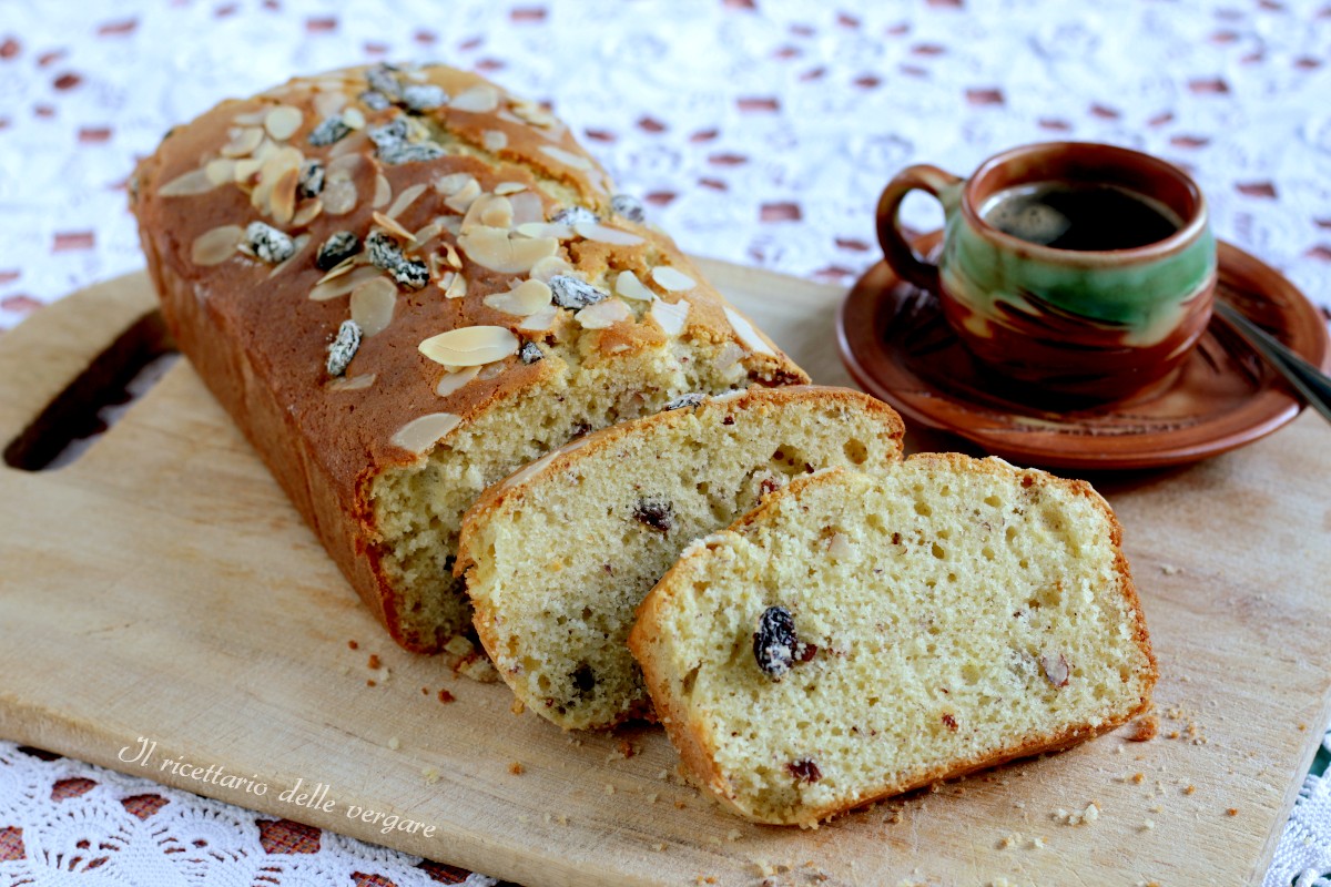 Plumcake soffice alle mandorle e uvetta tagliato a fette su un tagliere.
