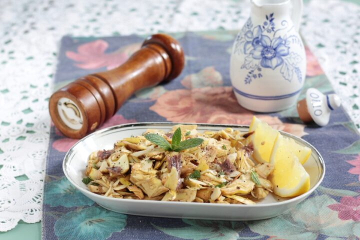 Piatto di carciofi crudi affettati con condimento di alici, mandorle e mentuccia.