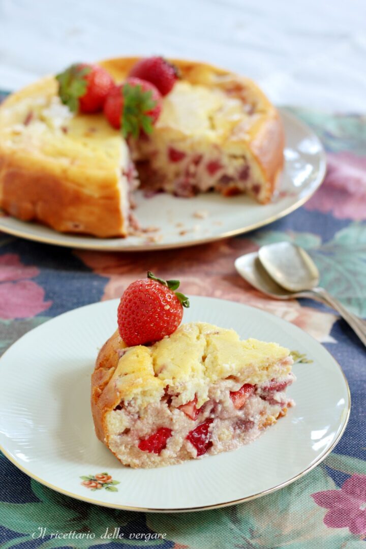 Una fetta di torta di ricotta e fragole senza farina in primo piano con la torta intera tagliata sullo sfondo.