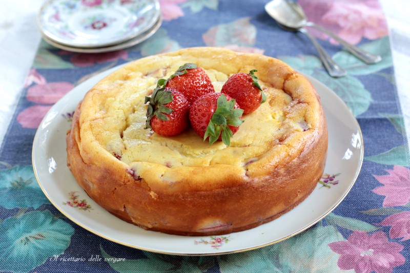 Torta di ricotta e fragole senza farina intera su un piatto decorato, guarnita con fragole fresche al centro.