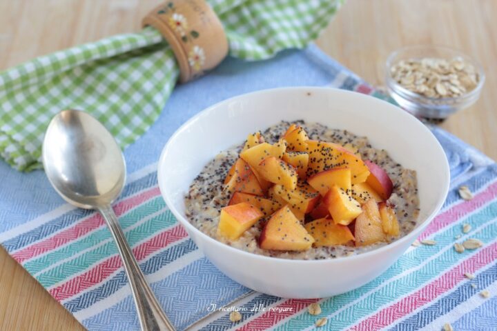 Porridge freddo estivo alle pesche senza cottura servito in una ciotola con cubetti di frutta fresca e cannella