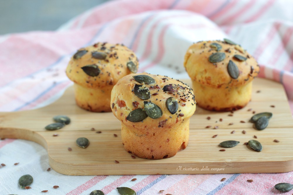 Muffin salati ai formaggi decorati con semi di zucca e lino su un tagliere