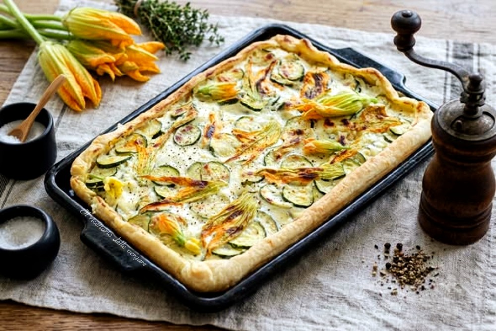 Torta salata con zucchine e fiori di zucca intere a raggiera, versione estiva e vegetariana.