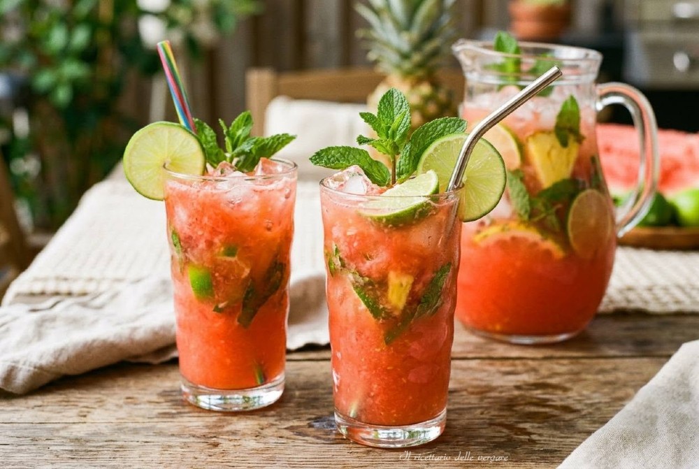 Bicchiere con bevanda dissetante estiva all'anguria e ananas guarnita con menta e lime