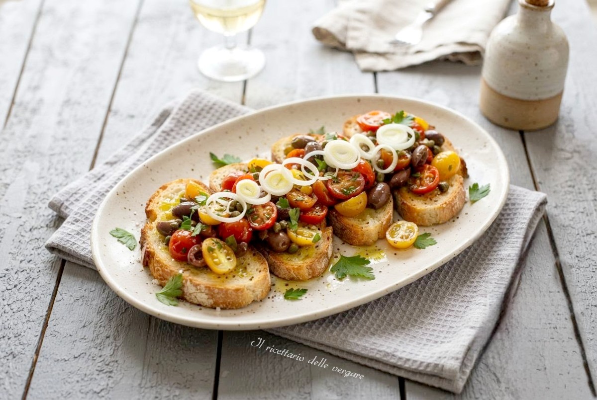 Bruschette con pomodorini saltati rossi e gialli, olive taggiasche, capperi e cipolla