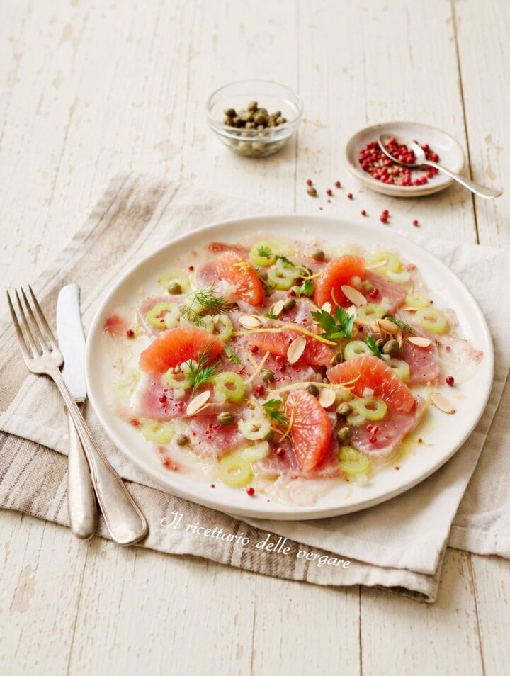 Inquadratura verticale del carpaccio di tonno con pompelmo rosa, sedano e capperi