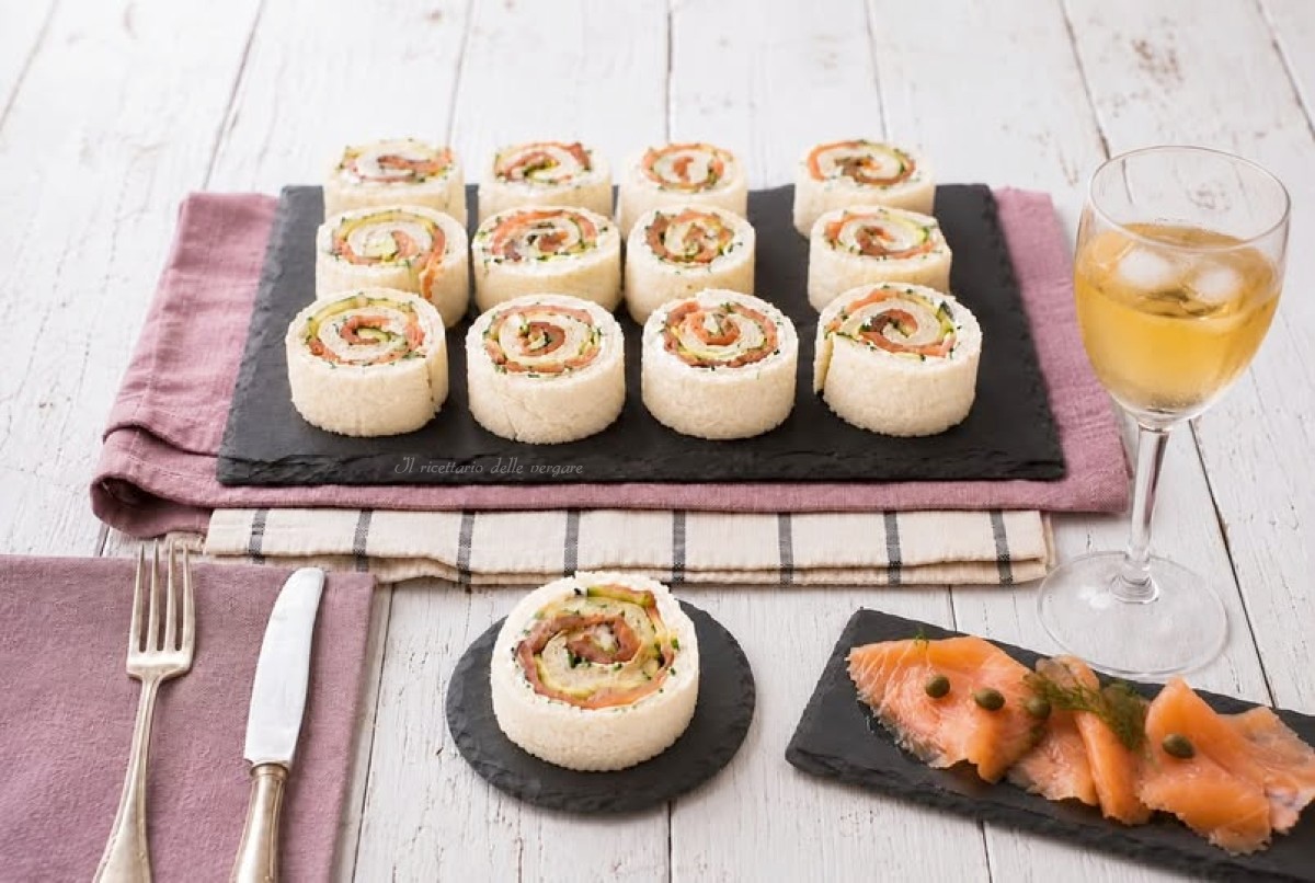 Vassoio con girelle di pane per tramezzini con salmone affumicato e zucchine su una tavola estiva
