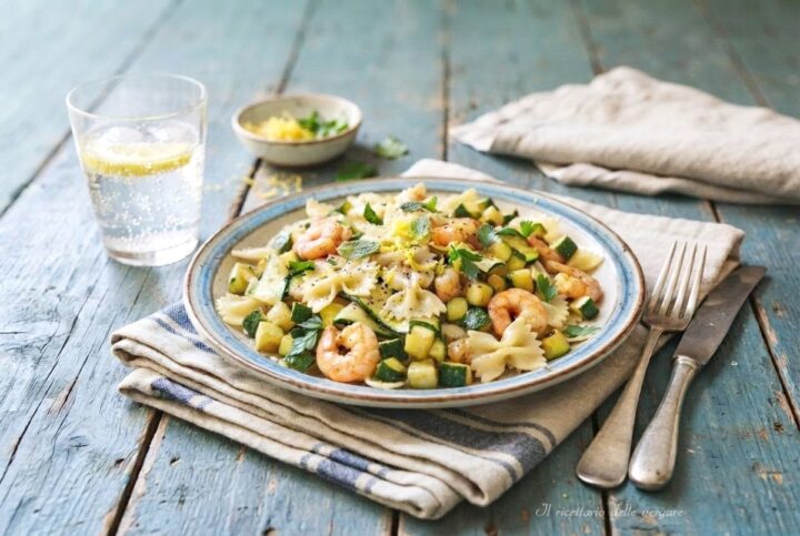 Piatto di pasta fredda con gamberetti e zucchine guarnito con menta fresca