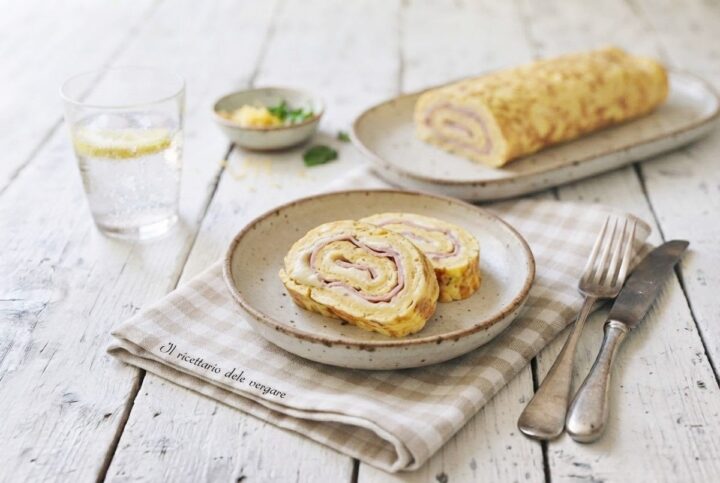 Fette di rotolo di frittata al forno farcito con prosciutto cotto e formaggio fuso su un piatto