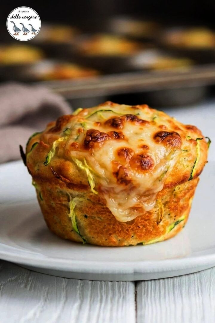 Primo piano ravvicinato di un muffin salato alle zucchine con crosticina di scamorza fusa e dorata