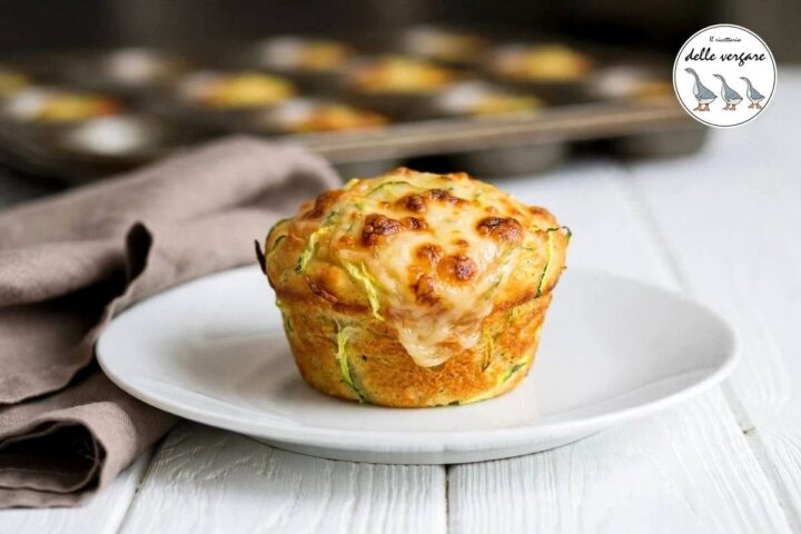 Un muffin salato alle zucchine con scamorza filante in superficie su un piatto bianco
