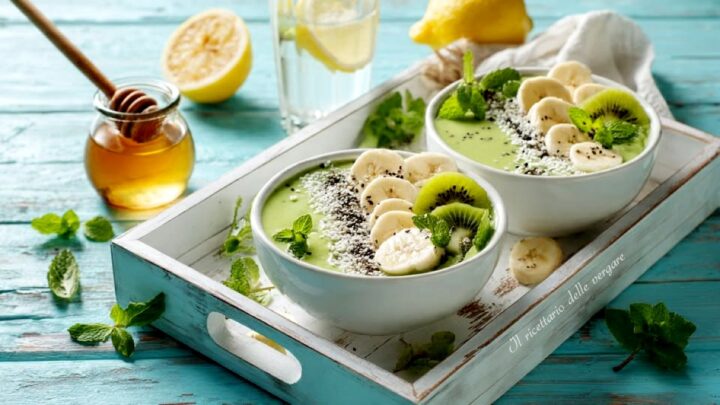 Due ciotole di frullato verde kiwi e banana con semi di chia disposte su un vassoio di legno bianco