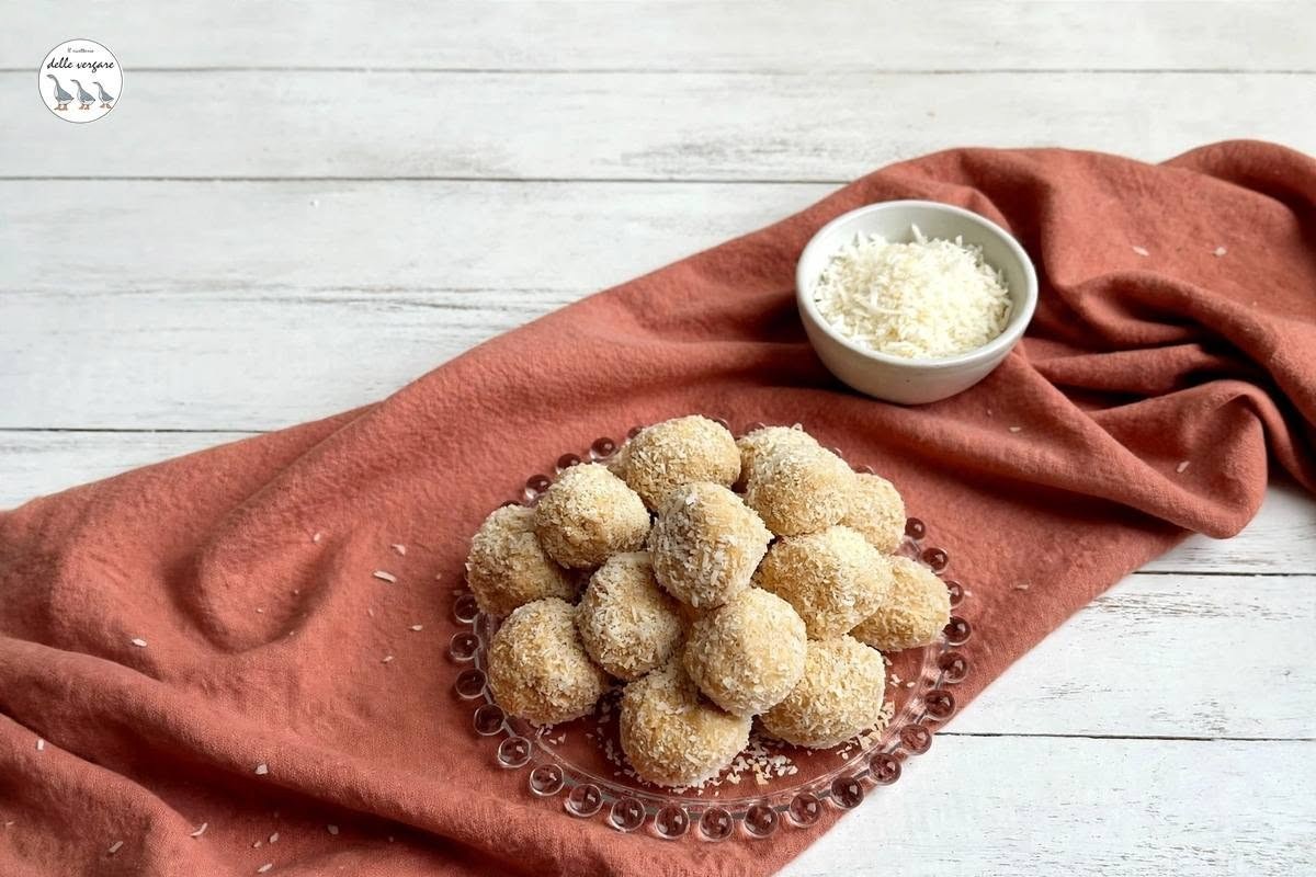 Un piatto da portata pieno di tartufini al mascarpone e caffè ricoperti di cocco grattugiato su un tovagliolo rosa.