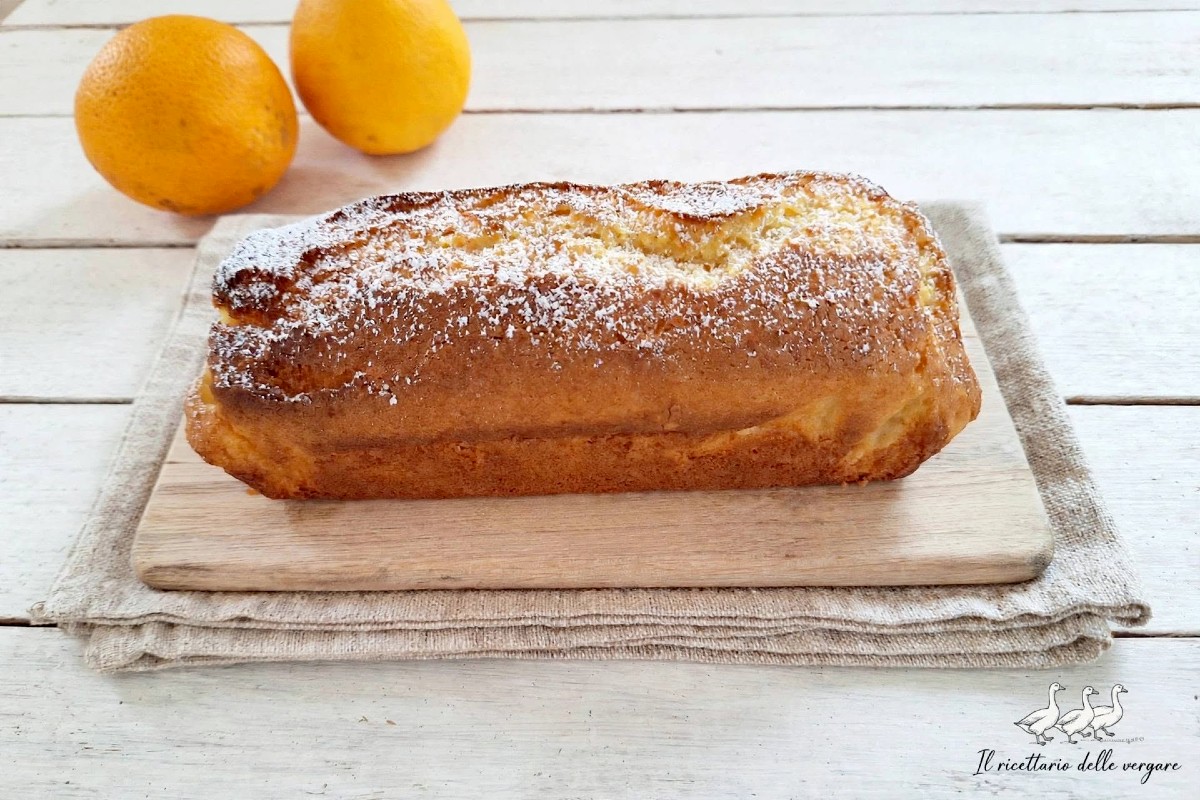 Plumcake all'arancia frullata intera cosparso di zucchero a velo su un tagliere