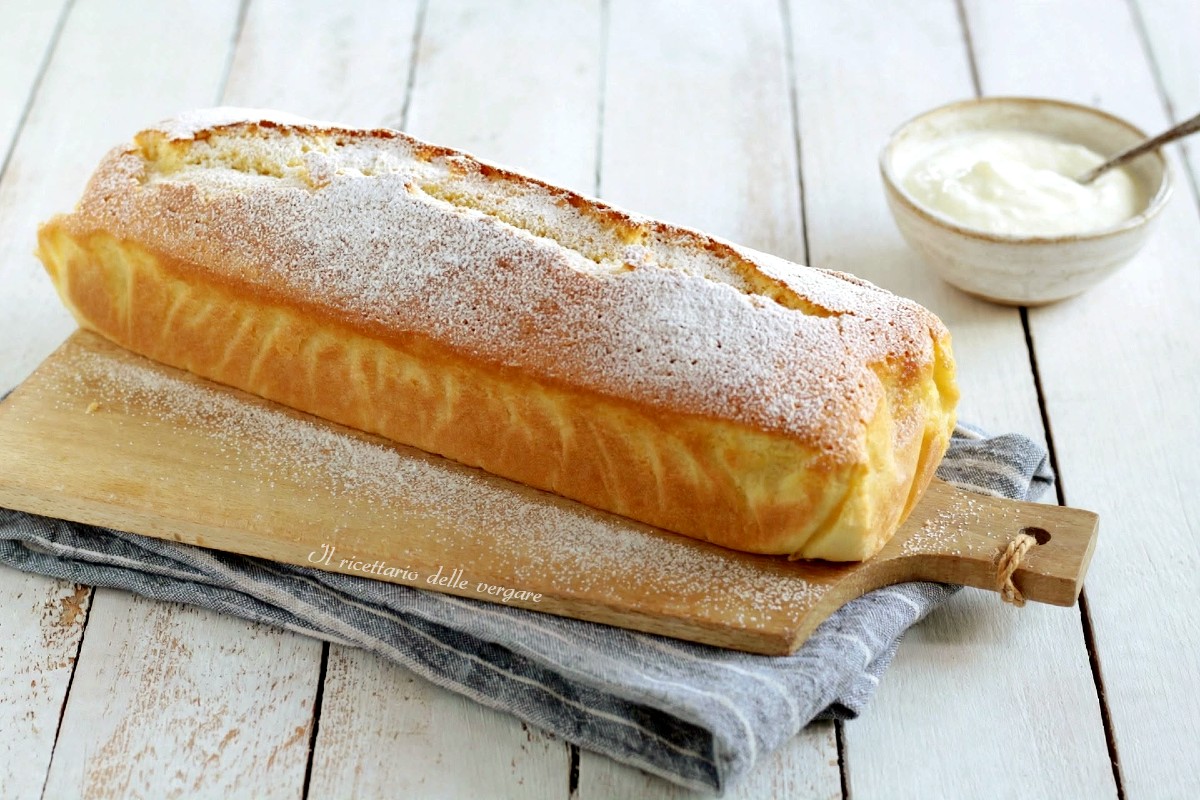 Plumcake allo yogurt senza burro soffice spolverato con zucchero a velo su tagliere di legno