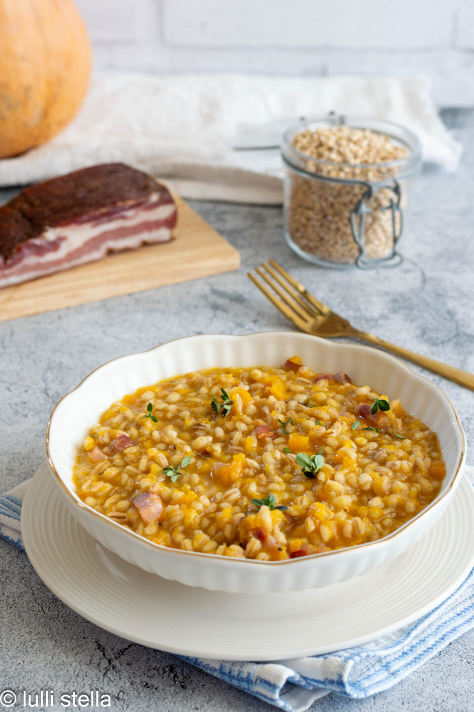 Orzotto alla zucca e speck nel piatto bianco, cremoso e invitante