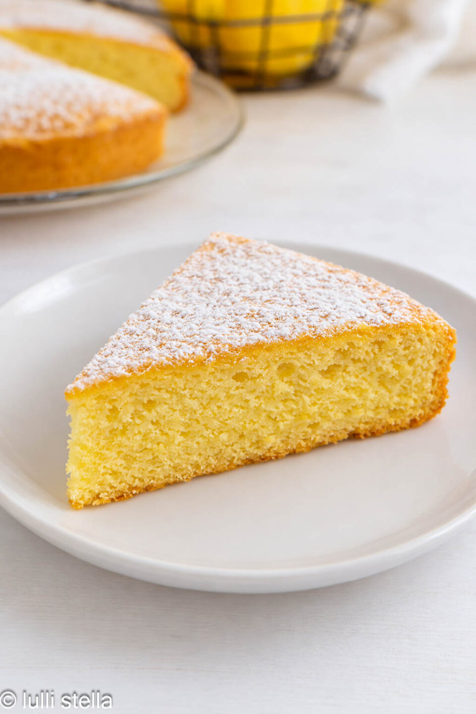Fetta di Torta Margherita al limone senza glutine, mostrando l’interno soffice e arioso dell’impasto profumato al limone"
