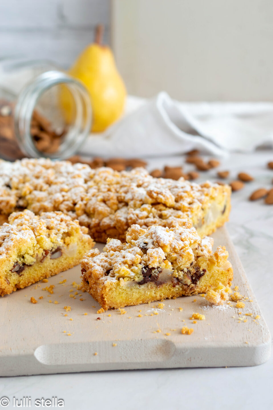 Sbriciolata senza glutine con pera, cioccolato fondente e mandorle, vista dall’alto su base rustica