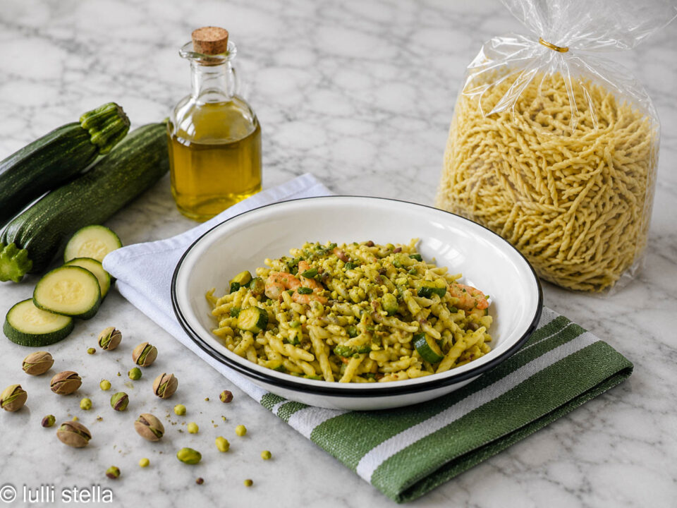 Pasta senza glutine con gamberetti e zucchine servita in piatto bianco