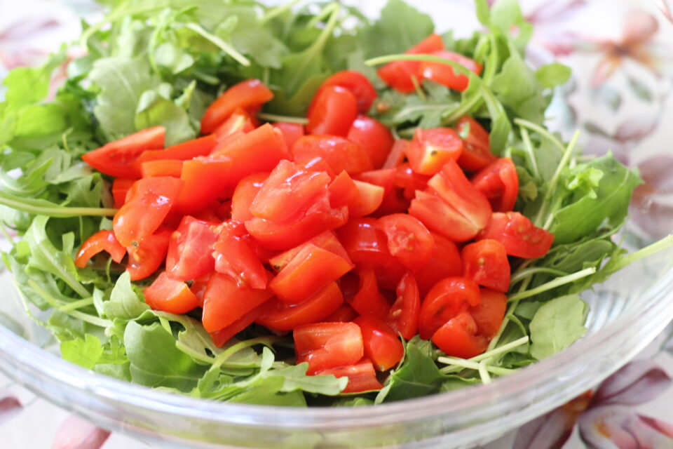 aggiunta dei pomodorini con rucola in ciotola
