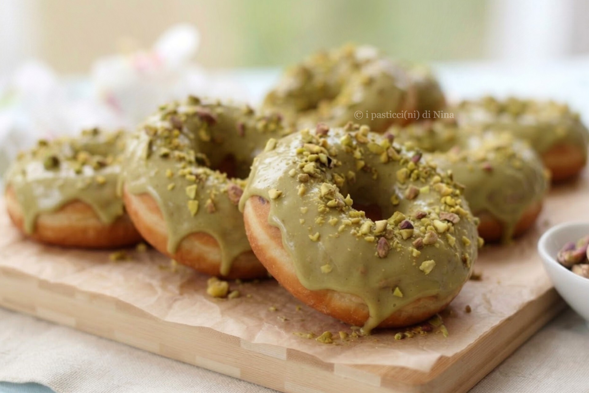 Deliziose ciambelline soffici, ricoperte da una golosa glassa al pistacchio e granella croccante, da preparare fritte o al forno.