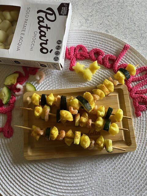 spiedini di gnocchi su tagliere di legno e tovaglietta bianca tonda