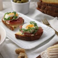 crostini con crudo, uovo sodo e ricotta