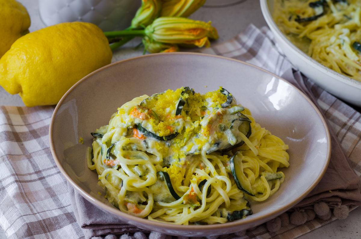 Pasta con zucchine, fiori di zucca, limone e panna: ricetta cremosa pronta in 20 minuti