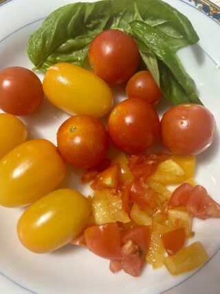 Pomodorini rossi e gialli con basilico fresco per preparare la pasta fredda estiva