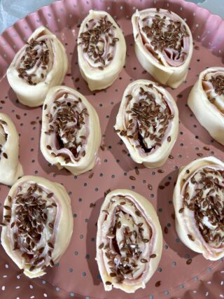 girelle di sfoglia crude con semi di lino disposte su teglia forata