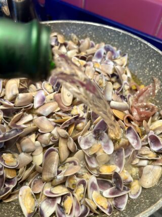 Sfumatura delle telline con vino bianco durante la cottura