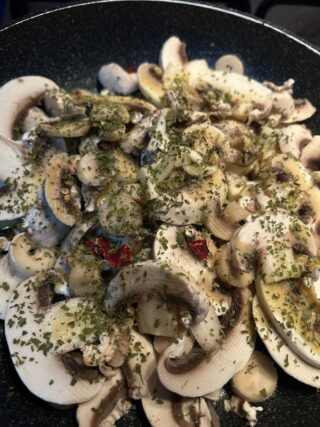 Funghi champignon crudi con aglio, peperoncino e prezzemolo in padella