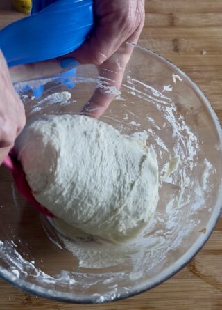 Impasto della focaccia steso nella teglia con le dita