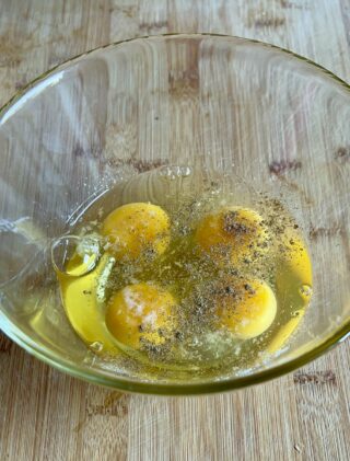 Girelle di frittata in padella preparazione con uova sale e pepe
