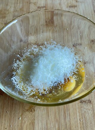 Aggiunta del parmigiano grattugiato alle uova per la frittata