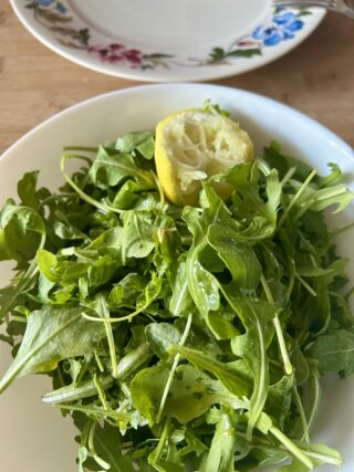 Rucola condita con olio, sale e limone per preparare la bresaola con rucola e parmigiano.