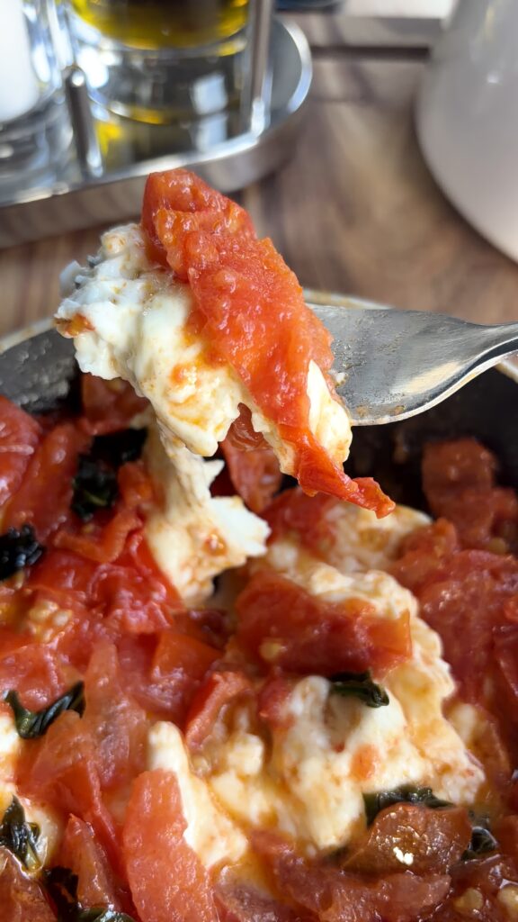 Primosale in padella con pomodorini morbidi e sughetto al pomodoro servito su una forchetta