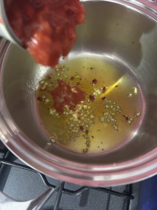 Preparazione del sugo di pomodoro con aglio, olio extravergine di oliva e peperoncino.