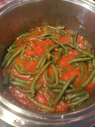 Fagiolini che terminano la cottura nel sugo di pomodoro.
