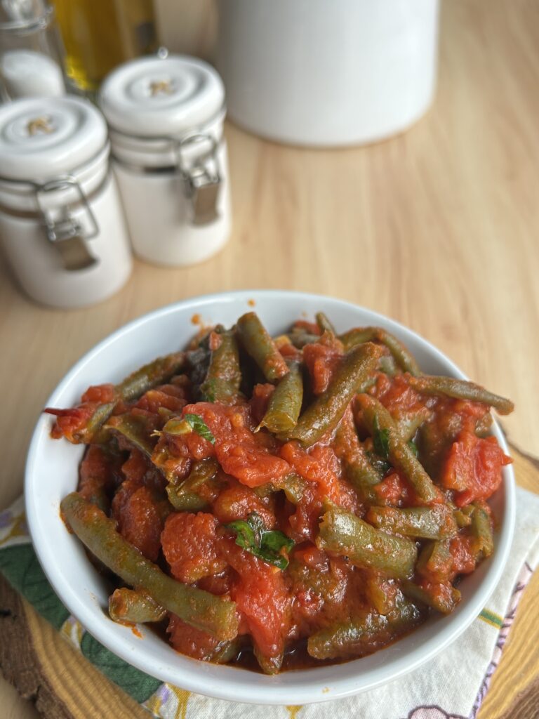 Ciotola di fagiolini al pomodoro con polpa di pomodoro, aglio, olio extravergine d'oliva e prezzemolo.