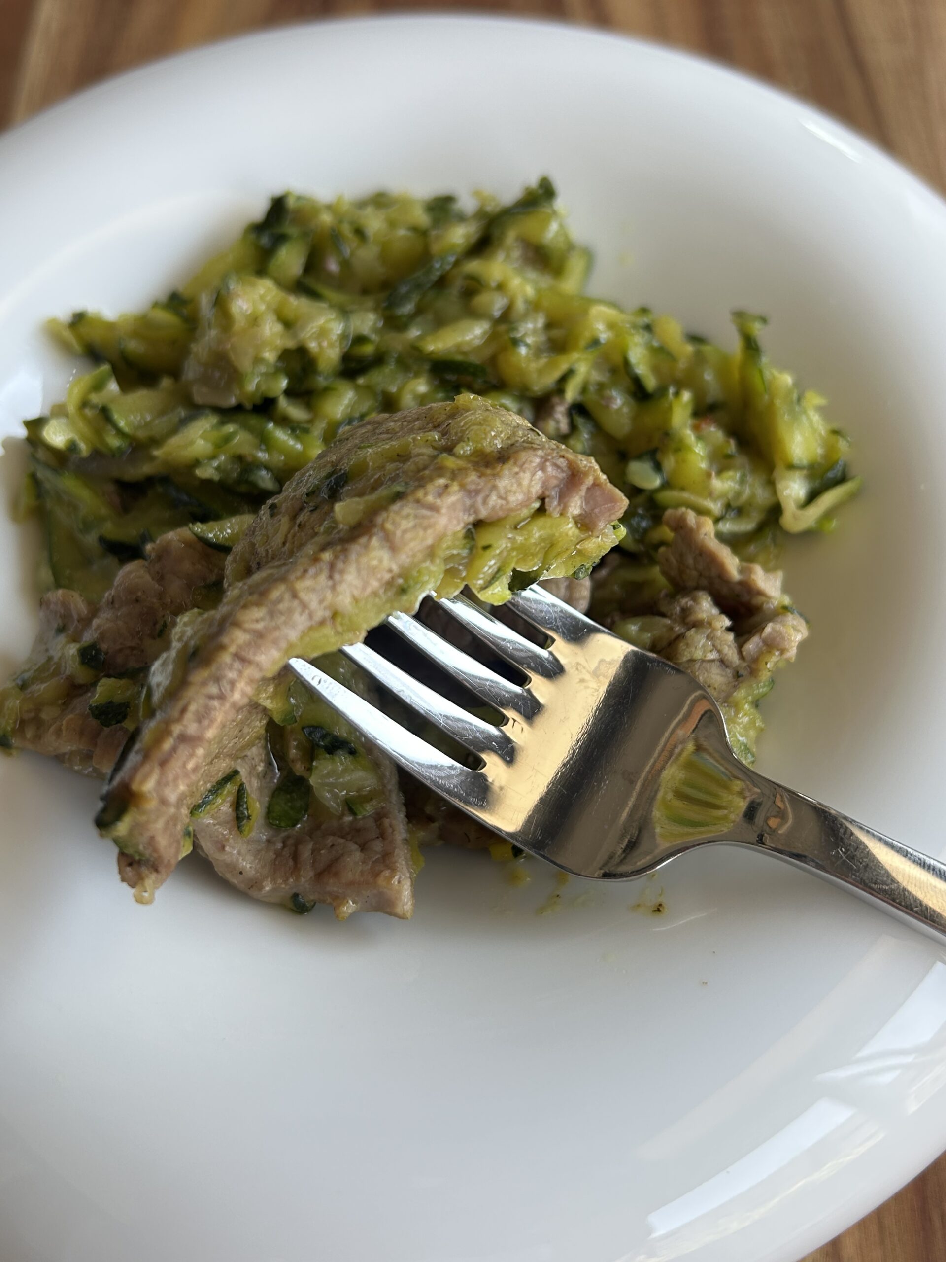 Primo piano delle fettine di manzo con zucchine cotte in padella.