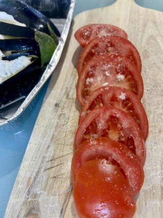 Melanzana farcita con fette di pomodoro e mozzarella prima della cottura.